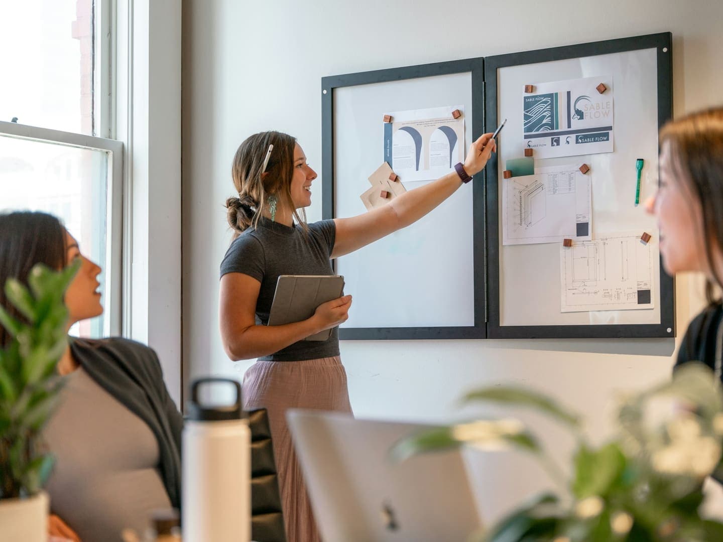 Deux collègues examinent des maquettes affichées sur un panneau dans un bureau